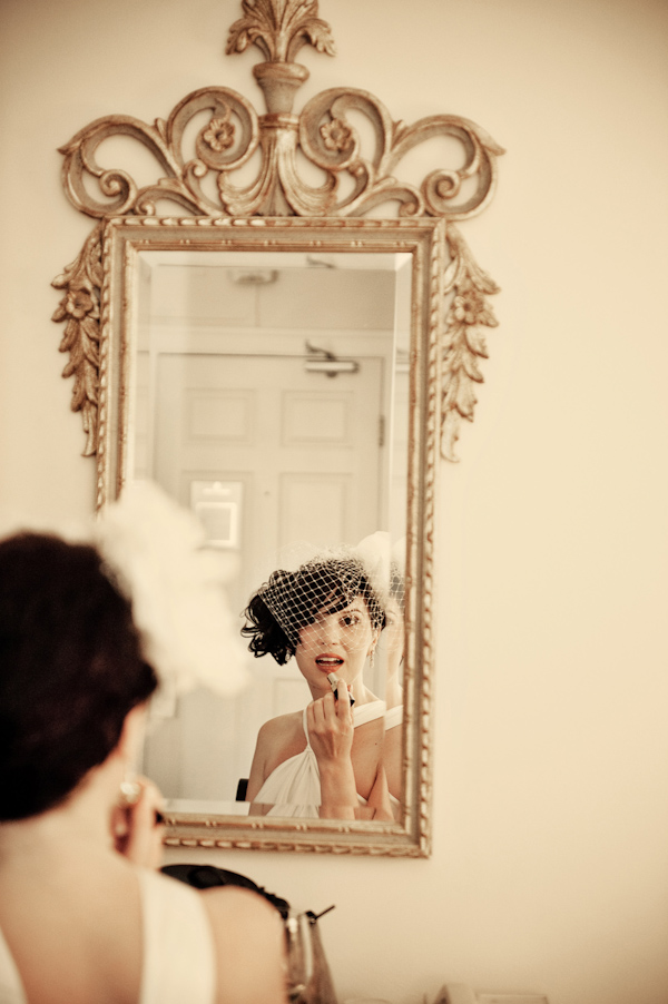 Beautiful bride wearing white birdcage veil looking in the mirror while applying lipstick - photo by Portland wedding photographer Barbie Hull 